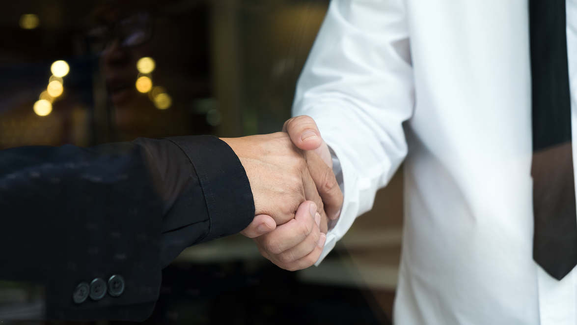 Two businessman shaking hands greeting each other Speedy Signs - Initial Financial Assistance